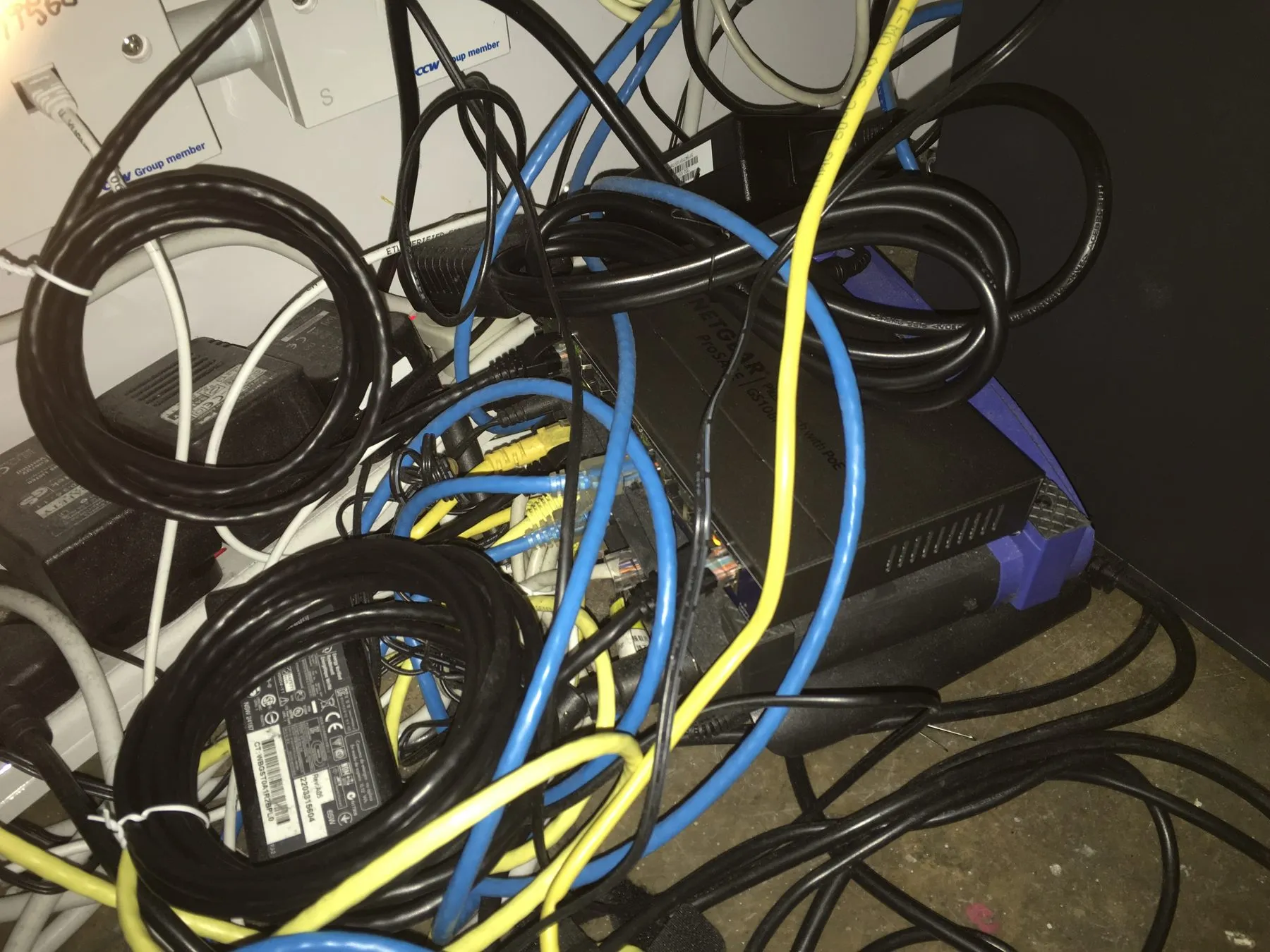 A tangle of network and power cabling behind equipment before the rebuild